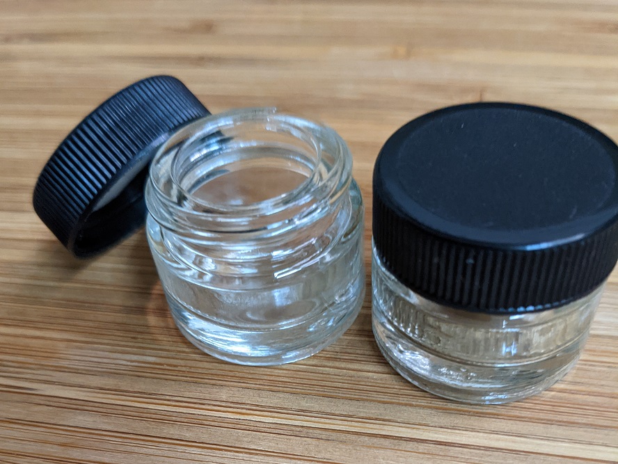 Two small glass jars with black plastic lids