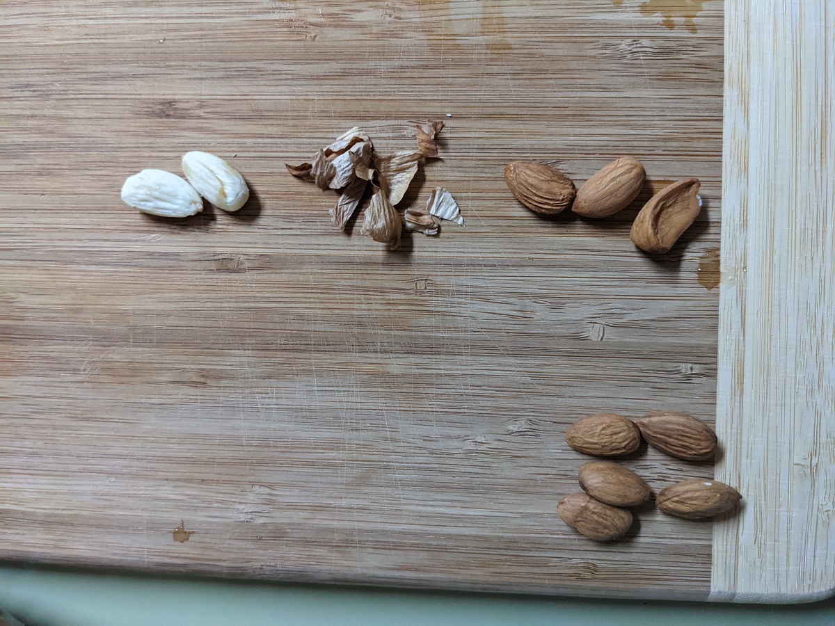 2 rows of almonds. the upper row has peeled almonds, peels, and soaked almonds. the bottom row are raw almonds