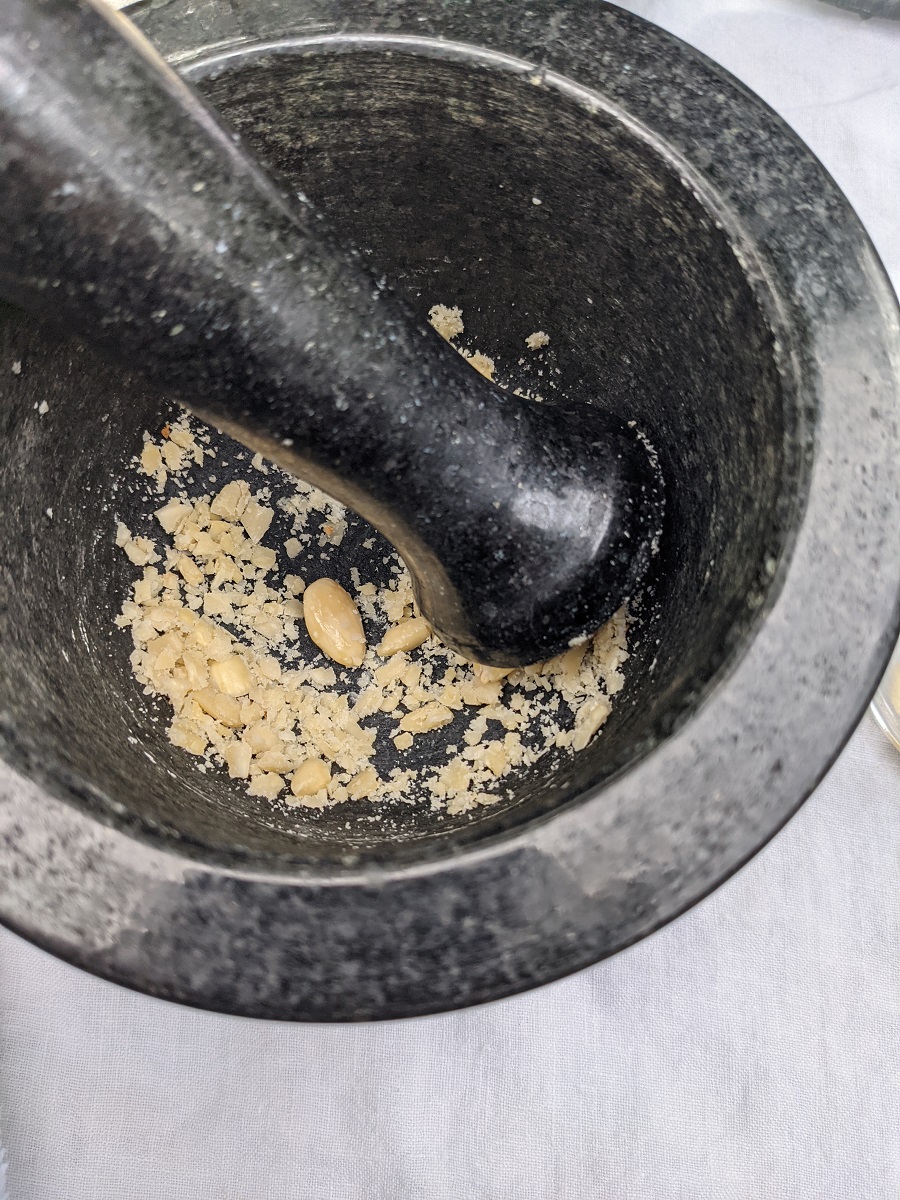 Black mortar and pestle with peeled almonds being ground