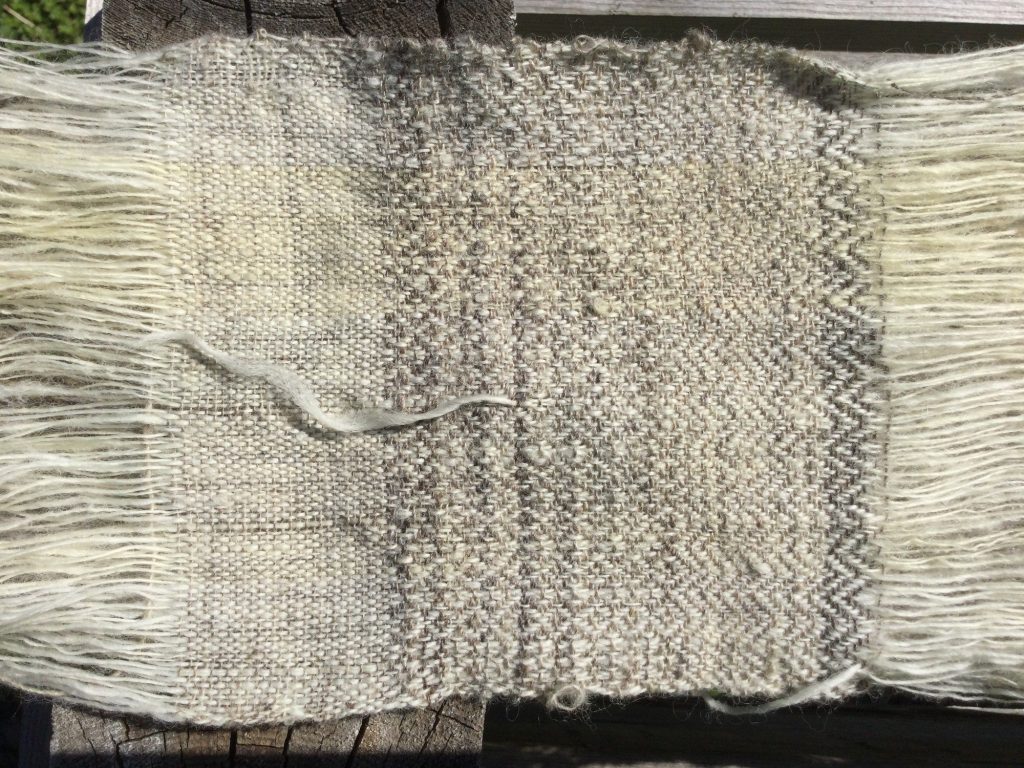 close up showing white threads woven with patterns of gray wool