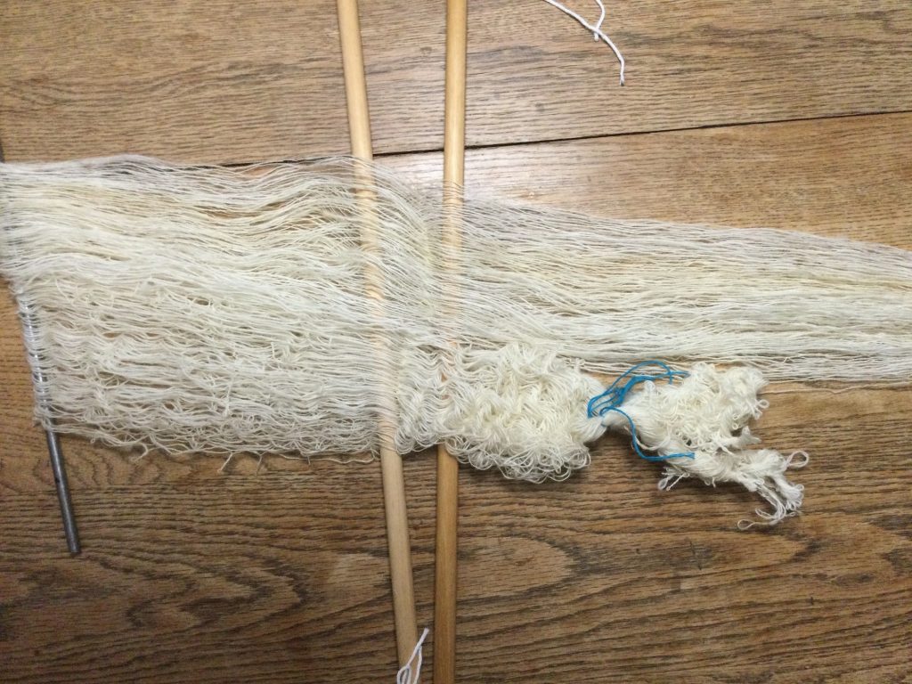 On a wooden table there are 2 skeins of white yarn 