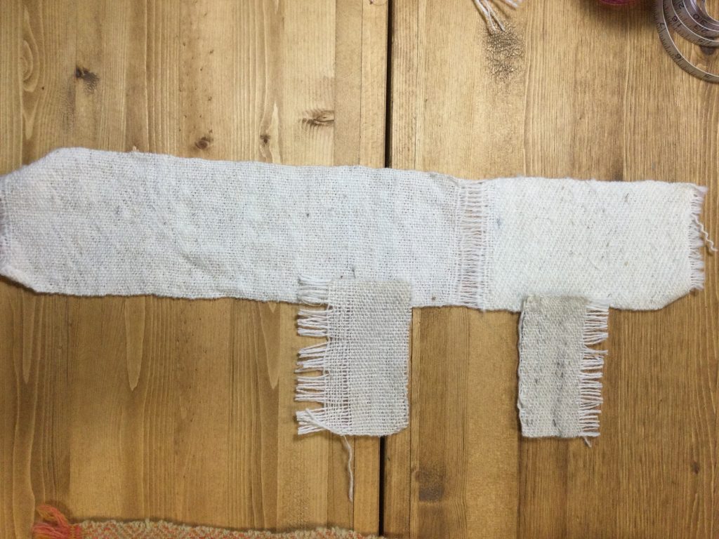 white wool sample washed with two small pieces unwashed, displayed on a wooden table