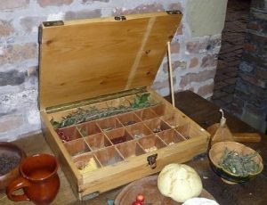 Wooden box with loose spices in compartments. Dishes of spices on the table around it