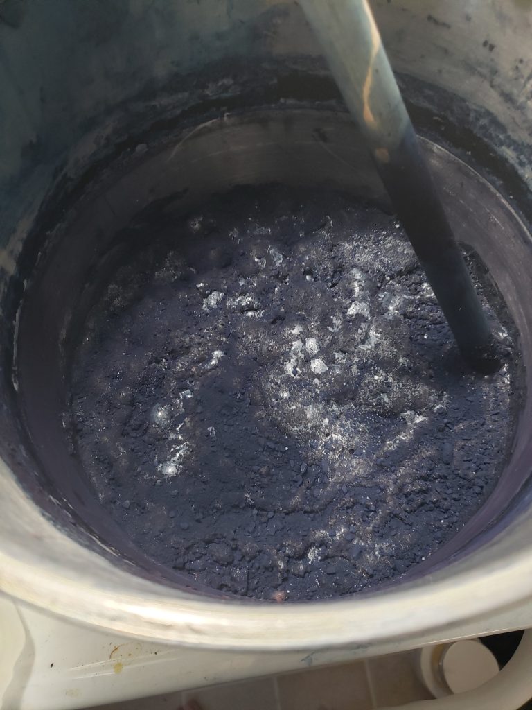 Stainless steel pot with blue powdered indigo mixed with white powdered lead