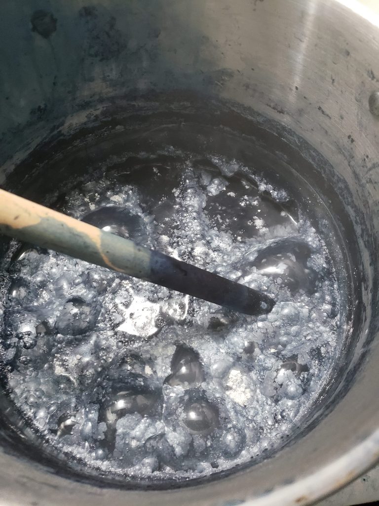 Vinegar reaction with powdered lead in stainless steel pot. White and blue bubbles