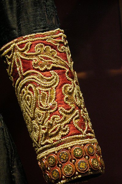 A red cuff on a blue sleeve decorated with pearls and enamel plaques